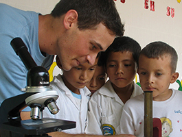 A teacher demonstrating a microscope to attentive students in a classroom setting, fostering curiosity and learning in science.